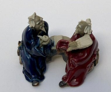 Ceramic Figurine Two Men Sitting On A Bench Holding Fan & Pipe- 2.0" Color: Red & Blue