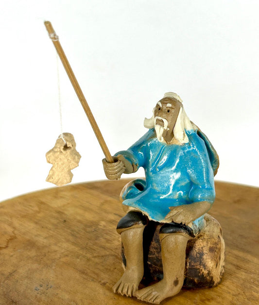 Miniature Ceramic Glazed Fisherman Figurine Sitting On A Log  Light Blue - 2.5"